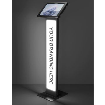 Photo en studio du support de sol noir Compulocks BrandMe Lumina Apex avec Microsoft Surface Pro 11, équipé d'un panneau de marquage éclairé.